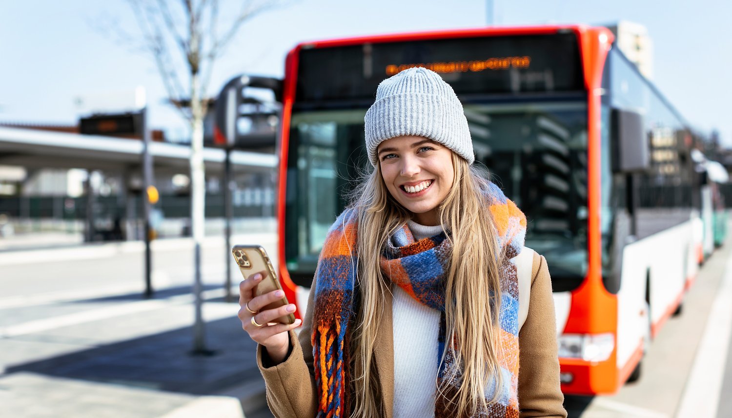 Junge Frau mit Handy vor Bus stehend (© VRS / Smilla Dankert)