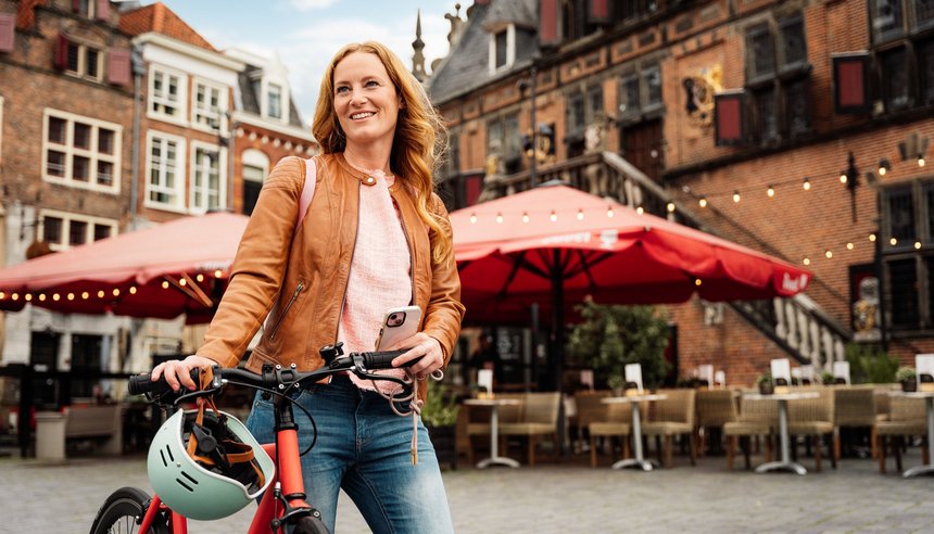 Frau schiebt Fahrrad durch Innenstadt