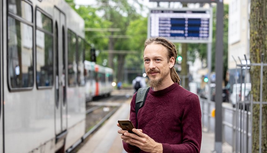 Fahrgast mit Handy an Stadtbahn-Haltestelle (Symbolbild)