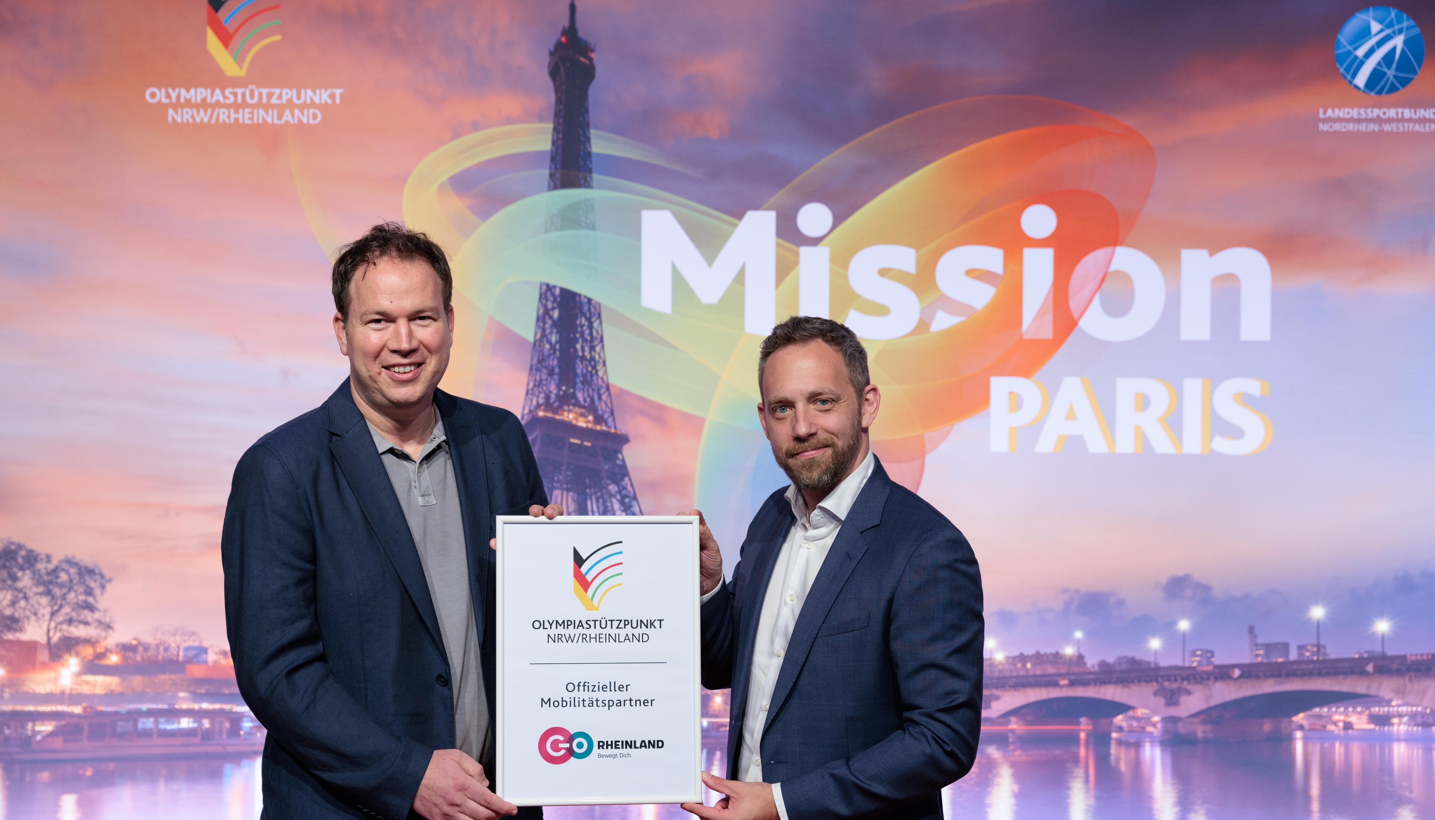 Marcel Winter (Geschäftsführer go.Rheinland) und Daniel Müller (Leiter des Olympiastützpunkts (OSP) NRW/Rheinland) halten Kooperations-Urkunde hoch.