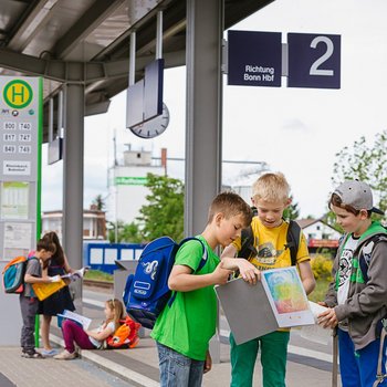 Schüler mit Schulranzen und Heften am Bahnsteig