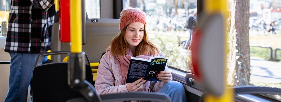 Junge Frau lesend in Stadtbahn