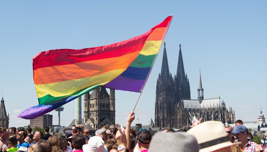 Eine Regenbogenflagge vor dem Kölner Dom