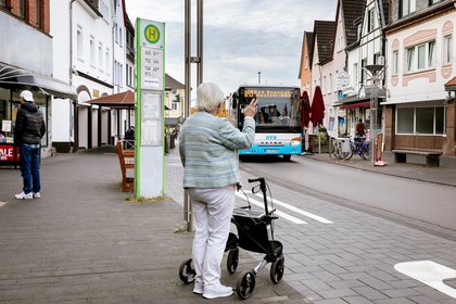 Frau mit Rollator an Bushaltestelle