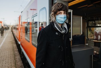 Frau mit Maske am Zug (AdobeStock_396439644)