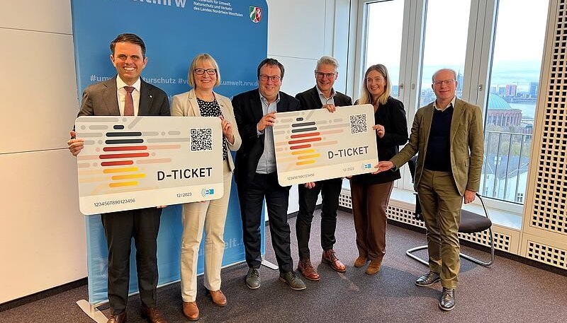 Eine Gruppe Personen hält Werbeversionen vom Deutschlandticket
