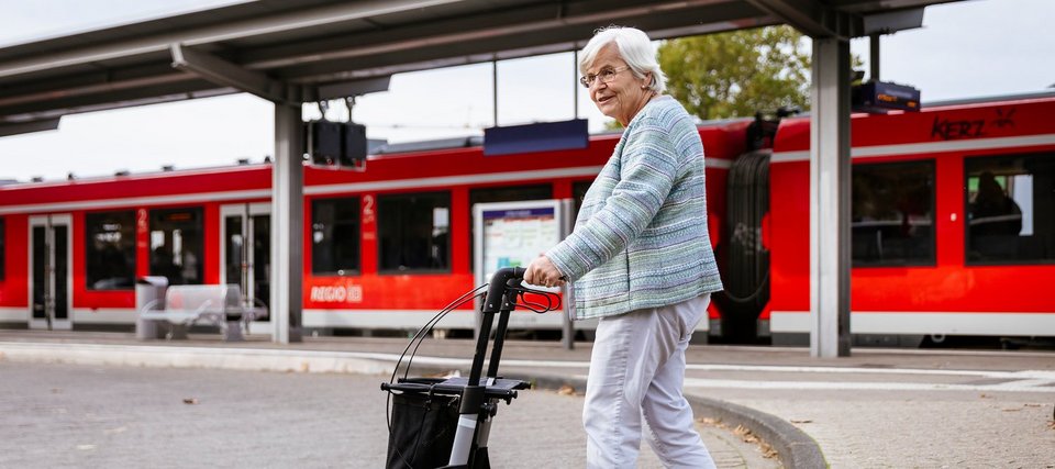 Frau mit Rollator an Bahnhof