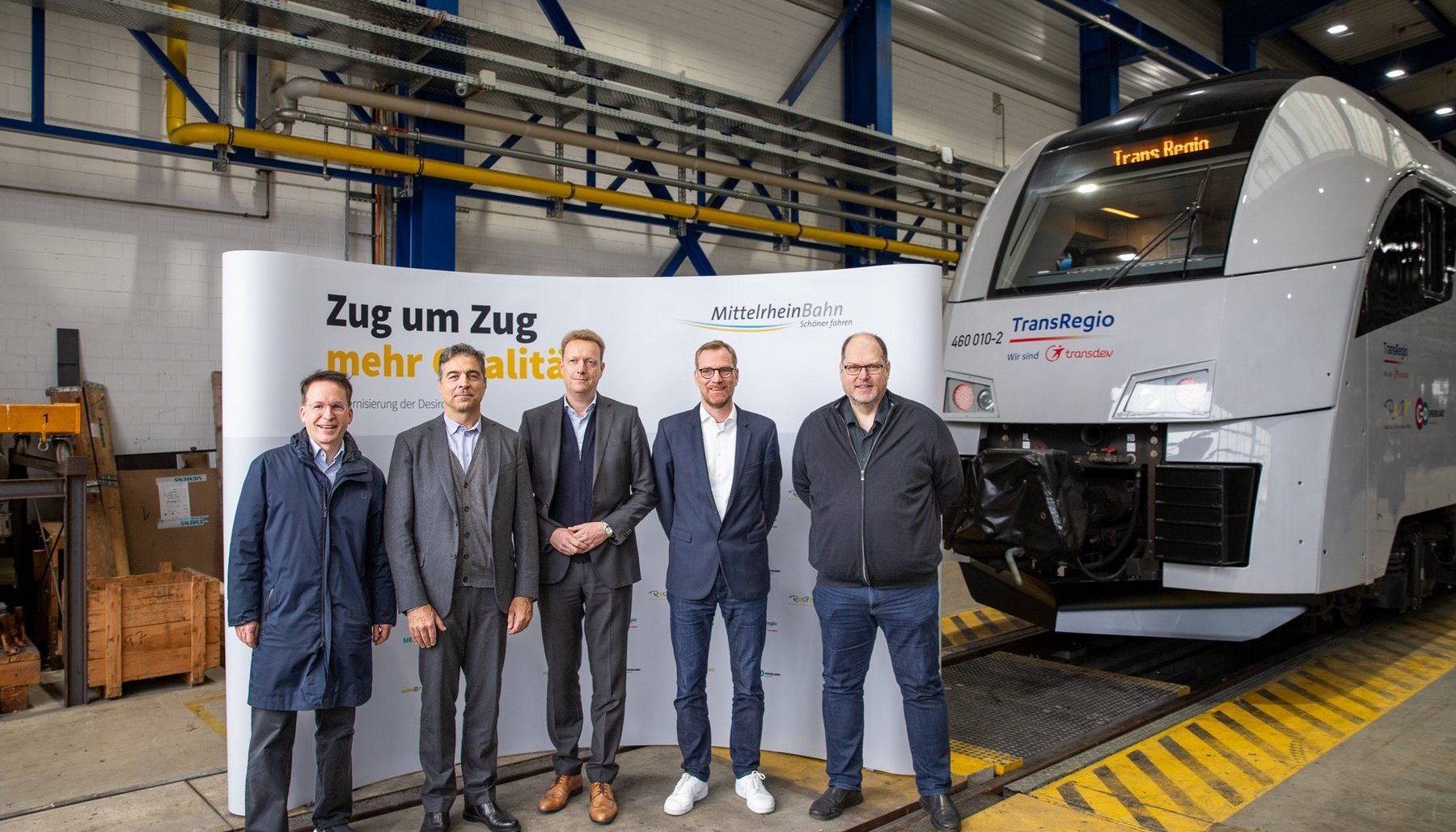 Fünf Personen stehen vor dem neuen Zug