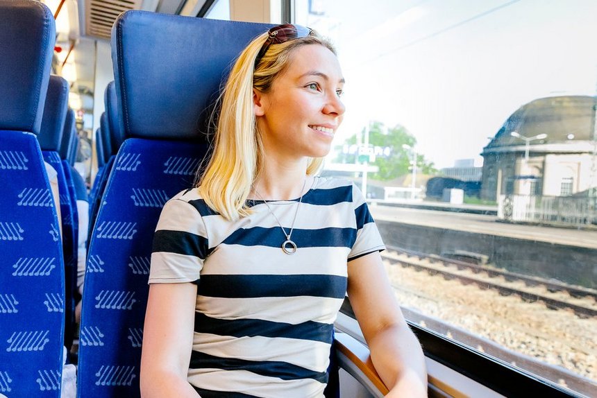 Junge Frau in Regionalzug, aus dem Fenster schauend