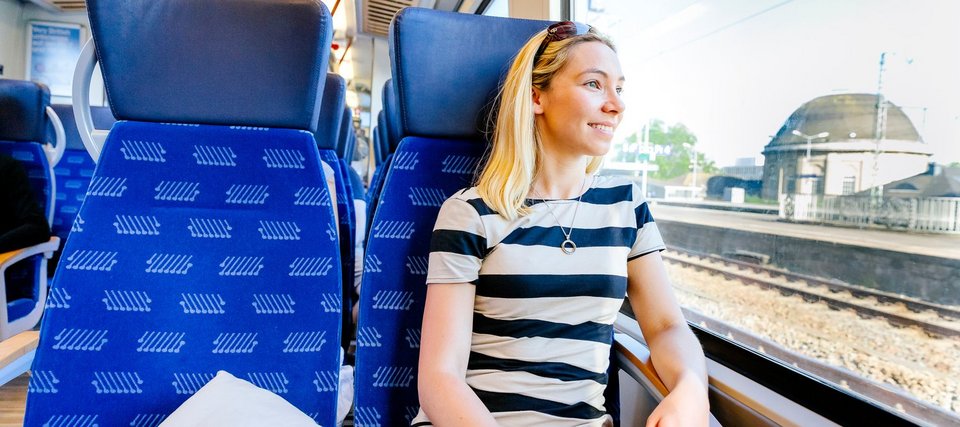 Junge Frau in Regionalzug, aus dem Fenster schauend
