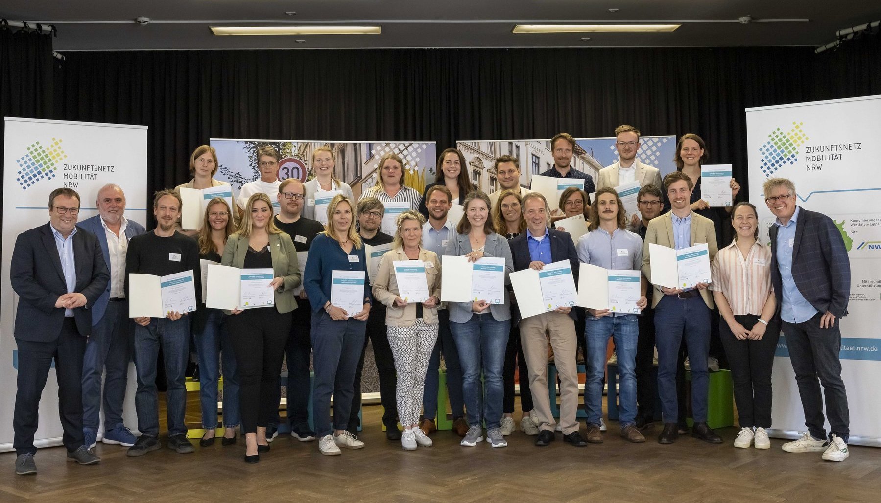 Eine große Gruppe von Personen die Urkunden halten.