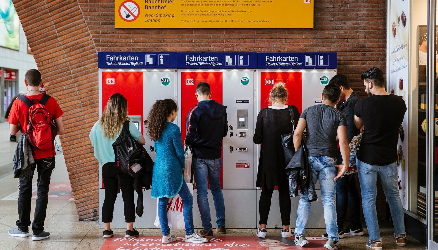 Personen stehen vor Ticketautomaten.