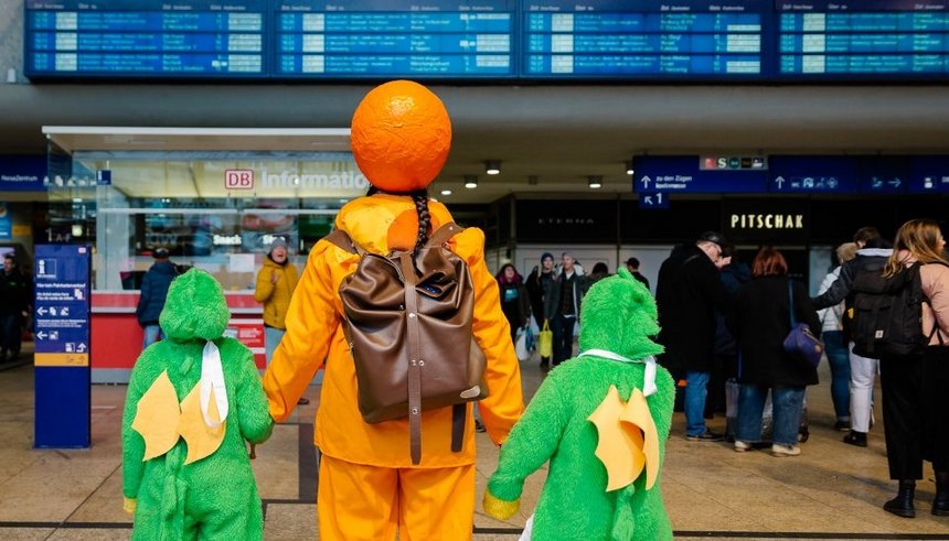 Karnevalisten schauen auf Fahrtzielanzeige im Kölner Hauptbahnhof